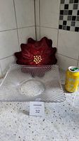Photo showing two decorative glass bowls: a clear square ribbed glass bowl and a red flower-shaped glass bowl next to a soda can for scale