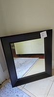 Full view of rectangular mirror showing dark wood frame and clear glass.