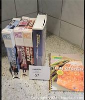 Photo showing three Winsor Pilates VHS tapes and the spiral bound recipe book Thin Kitchen laid on tiled floor.
