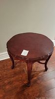 Full view of large round cherry wood end table showing top surface and legs.
