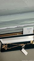 Gold-tone costume jewelry necklace with circular disc pendants in a dark green velvet box (box not included).