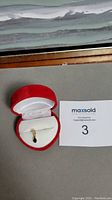 Genuine sapphire pendant placed inside a red velvet jewelry box with white satin lining, displayed next to lot number.