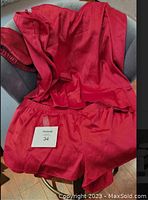 Silky red lingerie garment laid out showing top and shorts with a tag indicating size 34.