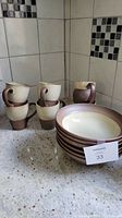 Photo showing six large bowls stacked with visible mauve rim and five mugs stacked with large curved handles.