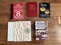 Six coin and antique guide books laid flat on wooden surface showing covers and titles.