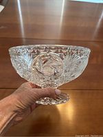 Side view of the clear crystal candy dish held in hand showing detailed cut patterns and pedestal base.