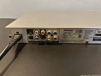 Back panel of Panasonic DVD/CD player showing various AV output ports and HDMI output with power cable connected.