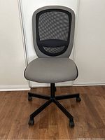 Front view of grey upholstered swivel office chair with mesh backrest and black five caster wheel base.