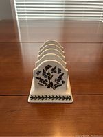 Front side of bread holder with botanical floral design and green leaf border on base