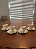 All four teacups and saucers set arranged on wooden table in natural light.