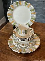 Stacked set showing dinner plates, bread plates, bowls, and a cup with the colorful Viscount pattern at the rim.
