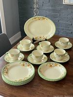 Photo showing all pieces including platter, teacups, saucers, dinner plates, and soup bowls arranged on dining table.