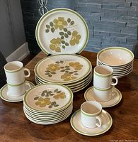 Full set of Islanderstone dinnerware in Oahu floral pattern arranged showing multiple plates, bowls, cups, and saucers.