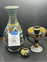 Three Gouda pottery pieces against black background showing large vase, small jug, and candle holder