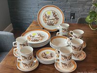 41 pieces Johnson Brothers Ironstone Bamboo dishes arranged on table showing dinner plates, side plates, bowls, cups, and saucers with distinct bamboo leaf and sun pattern in brown, yellow, and orange.