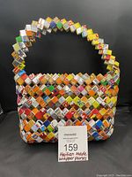 Full front view of one handmade wrapper bag showing colorful folded candy and food package wrappers forming the surface and handle.