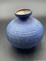 Blue round pottery vase with flared neck, showing textured matte blue glaze and subtle color variations.
