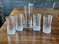 Five Iittala glasses arranged on wood table, 4 textured champagne glasses and 1 larger heavy glass