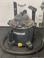 Mastercraft shop vac with hose and attachments shown from front and side, dusty and used.