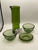 View of the green glass carafe with the three glass dishes in front showing shape and color