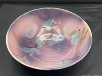 Top-down view of the signed studio art porcelain bowl showing the purple and green floral design and glossy finish.