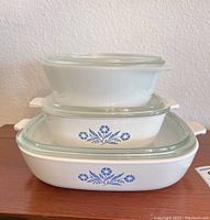 Stacked vintage Corning Ware blue cornflower pattern serving dishes with glass lids