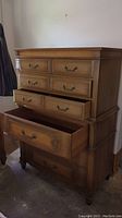 Front full view of vintage brown wood tall dresser with drawers partially open showing interior and metal hardware handles.