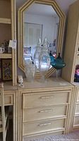 Dresser front with attached mirror, showing decorative handles and some glass decor on top.