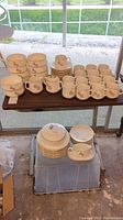 Full set of vintage RX Pharmacy dishes displayed on a table and crate, showing cups, saucers, plates, bowls, and serving pieces.