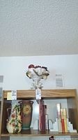 Wide shot of shelf showing three vases, books, two sets of bookends.