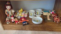 Wide view of all items on wooden shelf showing Asian doll, Easter egg tray, Christmas ornaments, pharmacist mugs and ashtray, letter opener and Rx Rolodex.