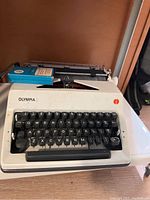 Photo showing the Olympia manual typewriter with white body and black keys, in untested and used condition.