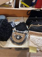 Photo showing a collection of vintage purses including black textured crocheted bag, black beaded purses, beige and white embroidered purses, with varying designs and embellishments.