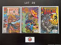 Three individual comic books bagged and boarded, issues 495, 496, 497 from 1996 featuring Thor, laid flat on a black surface under lighting showing vibrant cover art.