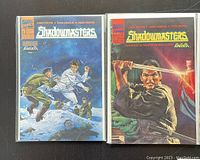 Close-up photo showing two of the Shadowmasters comics (issues 1 and 2) with clear cover art, Marvel Comics logo, and publication year visible. Comics are bagged and boarded.