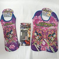 Photo shows two Ed Hardy neoprene beverage totes: one single bottle size on left and one double bottle size on right, with purple and pink skull and flower motif. Between them is the Ed Hardy Icing Koi tattoo faceplate Blackberry case in original packaging.