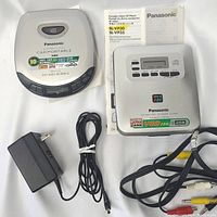 Panasonic SL-VP30 Portable Video CD Player with power adapter, AV cables, and user manuals displayed behind the unit