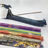 Blue dragon incense burner holding a single incense stick with five packs of incense sticks laid in front.