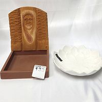 Photo showing the indigenous native carved wooden displayer with face and feather detail next to the Casamoderna white ceramic flower-shaped serving dish.