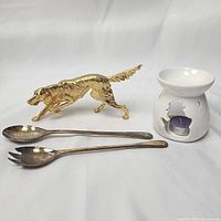 Photo of all items together: gold Irish Setter figurine, silver plated salad servers, and white ceramic snowman candle holder with tealight.