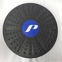 Top view image of the black round balance board showing knobby grip surface and blue logo in center