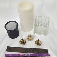 Photo showing the whole lot: cream LED wax candle, clear glass vase, black mesh pen holder, three brass incense cone burners, wooden incense stick holder, and HEM Opium incense sticks box.
