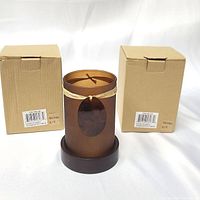 Photo showing two cardboard boxes and one glass candle holder with a dark wooden base, frosted brown glass with shell decoration tied with natural fiber.