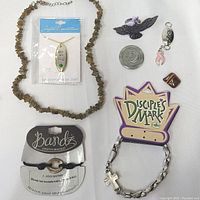 Photo of assorted inspirational jewelry items including stone necklace, bracelets, pendants, and tokens arranged on white background