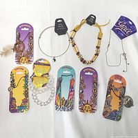 Photo showing nine new carded necklaces and chokers with various themes and materials arranged flat on white background.