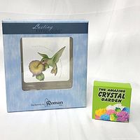 Boxed glass hummingbird plate with stand and boxed Amazing Crystal Garden kit side by side on white background.