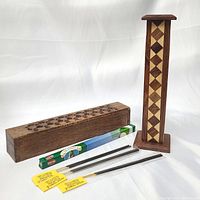 Wooden incense burner tower with diamond pattern inlay, wooden incense box holder, unopened incense sticks and three loose incense sticks shown on white background.