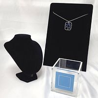 Black velveteen necklace bust display, black velveteen multi-necklace board with stone pendant necklace, and clear acrylic blue decor box shown together on white background.