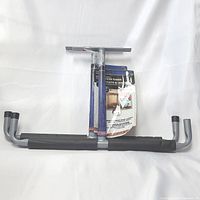 Full view of black heavy duty overhead storage hooks rack hanger with foam padded hooks and mounting hardware included, in original packaging.