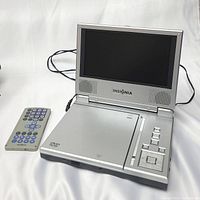 Insignia portable DVD player open with screen and control buttons visible next to remote control on white background.